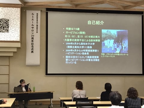 吉野由美子の講演風景、自己紹介がスクリーンに映し出され都いる。